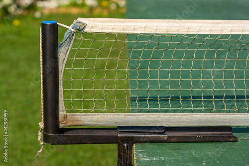 Weathered table tennis net stretched on old green tennis table © Sergei Gorin
