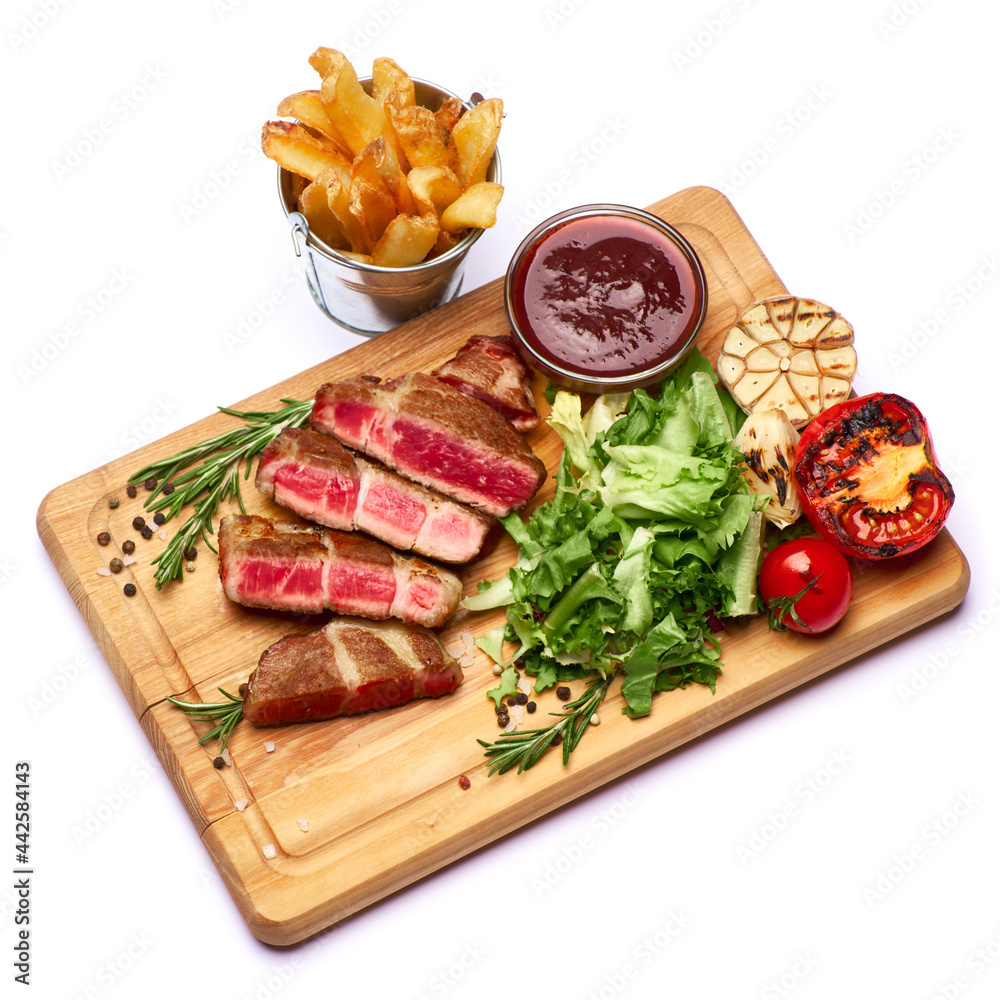 Grilled sliced roated beef steaks, potato and sauce on wooden cutting board