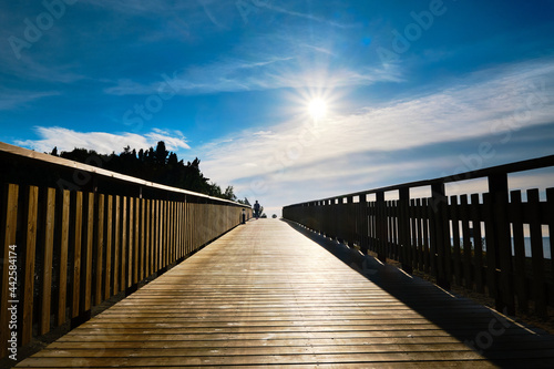Fototapeta Naklejka Na Ścianę i Meble -  The sun on the wooden boardwalk, next to the beach, in the warm morning sun, you can stroll along the boardwalk.
