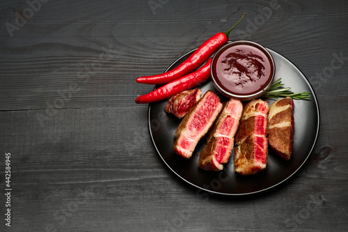 Grilled roated beef steaks on black ceramic plate