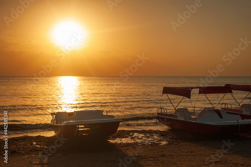 three catamarans stand on the seashore in the summer at sunset in the golden hour