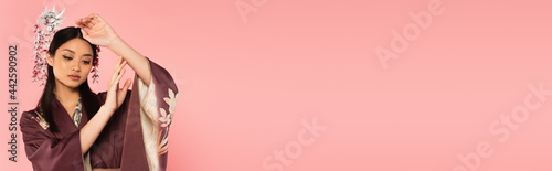 Japanese woman in kimono posing isolated on pink with copy space, banner