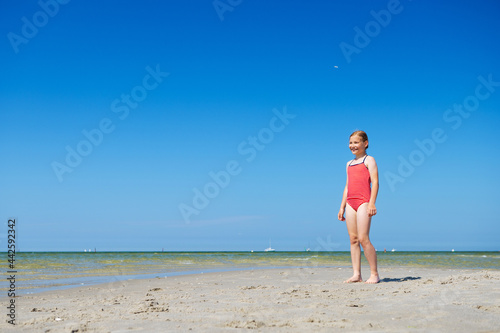 Cute child girl running and having fun on beach at summer day