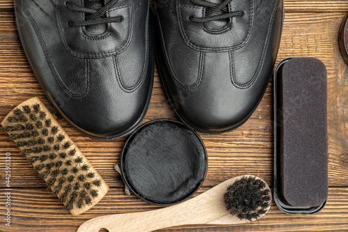 leather boots, brushes, shoe polish wax, footwear care products on wooden background