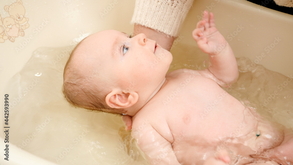 Cute baby boy looking at mother washing him in bath Cute baby boy looking at mother washing him in bath