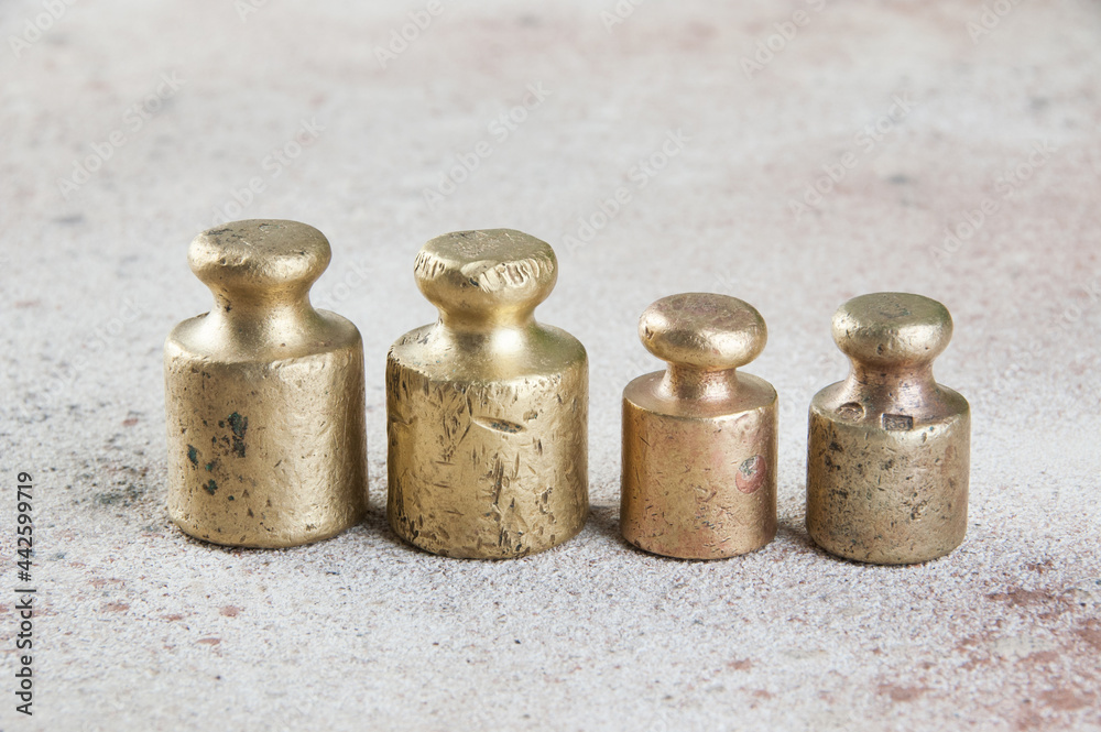 Four antique bronze weights for scales on concrete background. Four antique bronze weights for scales on concrete background.