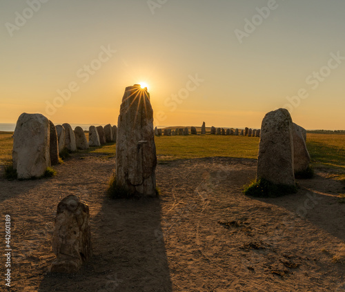 view of the prehistoric Ales Stenar ship setting on the southern coast of Sweden at sunset  with a sun star photo