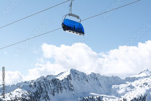 View of the snow-capped mountains and the cable car with blue chair cabins. Concept for sports, landscape, technology
