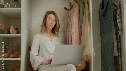 the girl behind the laptop sits on the cabinet and looks at the camera