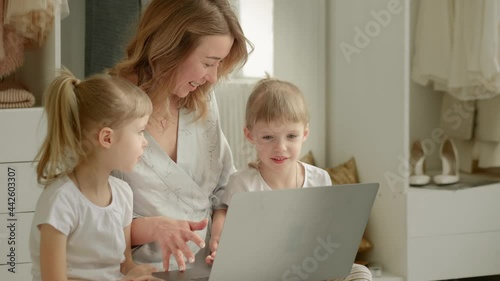mom with daughters blonde twins sitting at a laptop