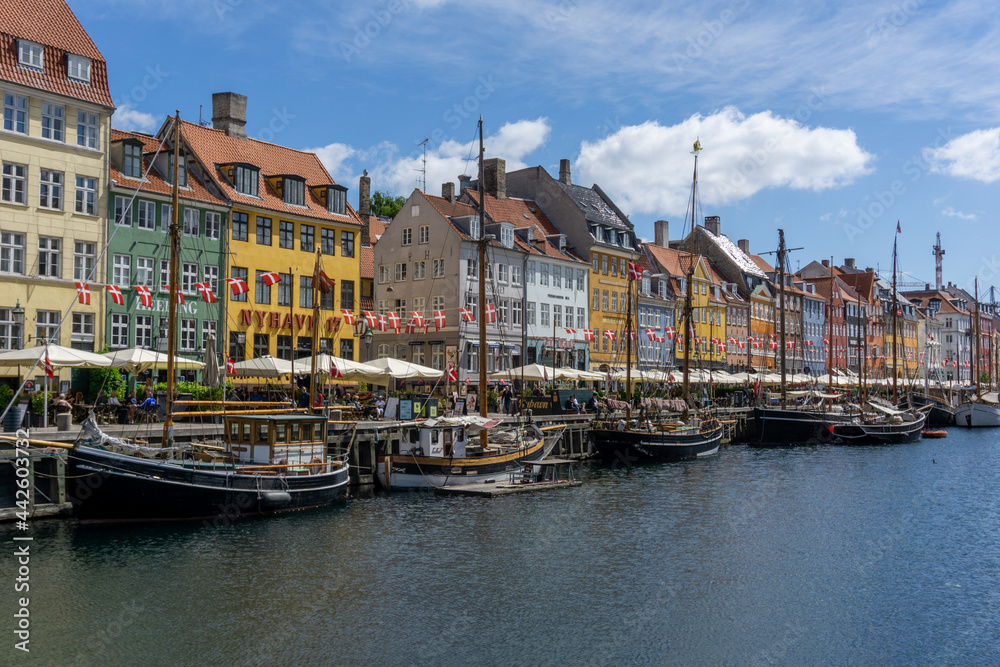 view of the historic Nyhavn quarter in downtown Copenhagen with a tourist boat cruise barge in the foreground