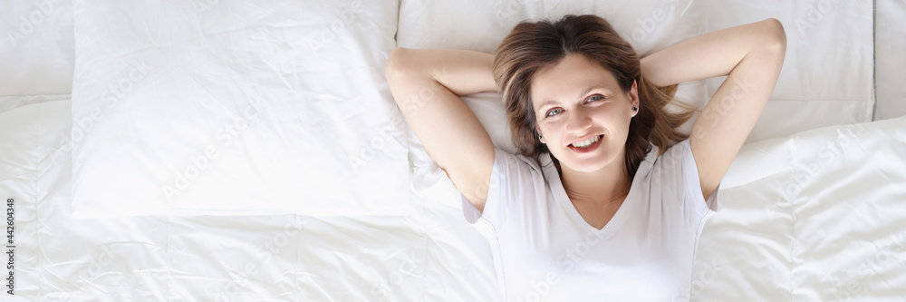 Smiling happy woman lies on white bed Smiling happy woman lies on white bed