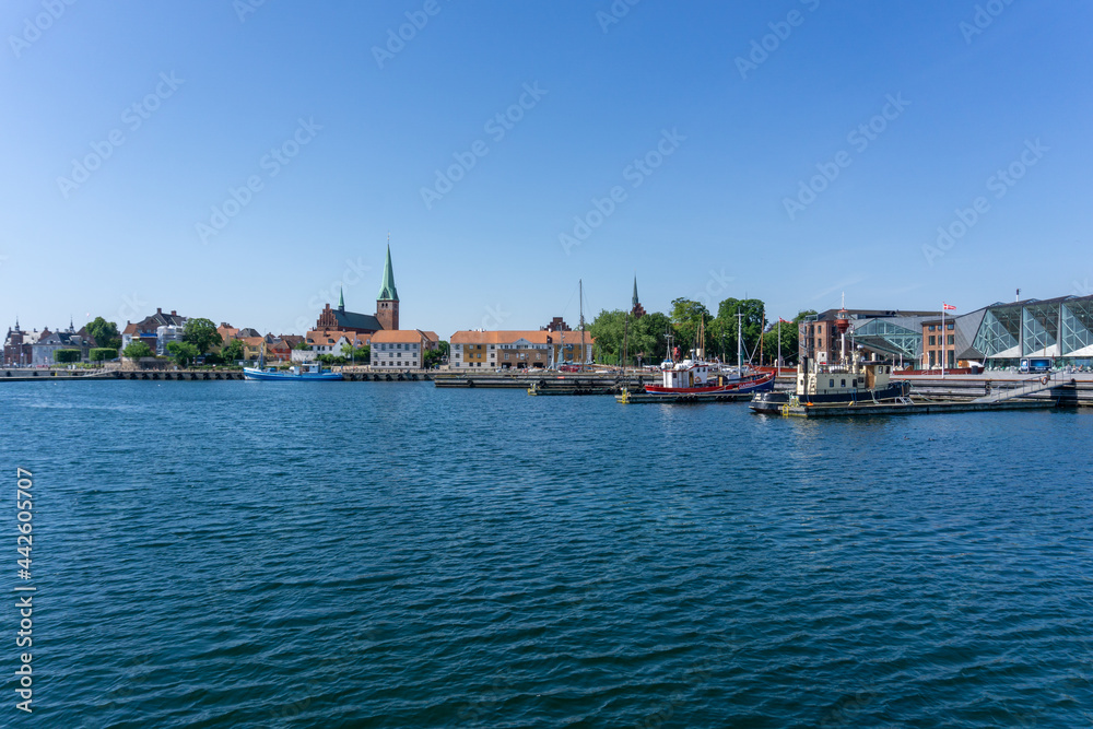 cityscape of the harbor and old town of Helsingor in northern Denmark with colorful fishing boats in the foreground