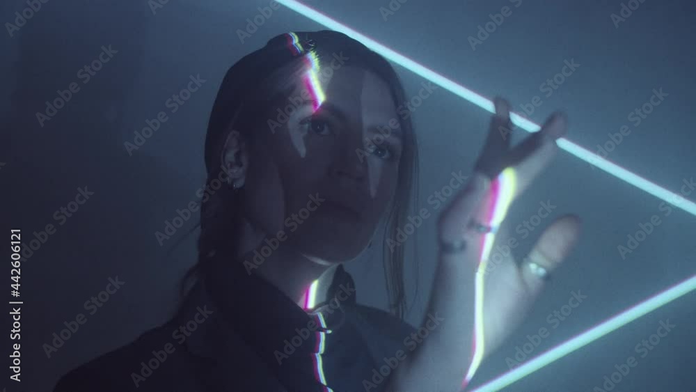 Young beautiful woman standing in dark studio with laser light projection and moving her arms