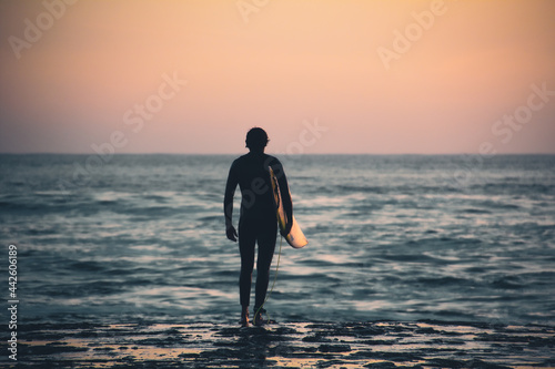 Surfer watching the waves at sunset in beach