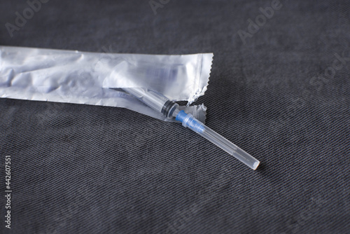 open and medical syringe with needle on gray denim background