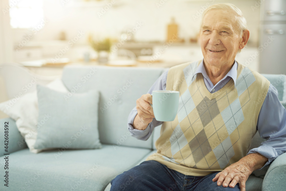 Happy old man resting on sofa with cup of tea Happy old man resting on sofa with cup of tea