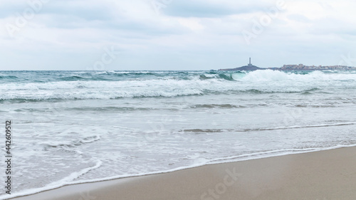 Stormy Mediterranean sea in overcast. Storm and lighthouse at the distance. Spain, la Manga del Mar Minor.