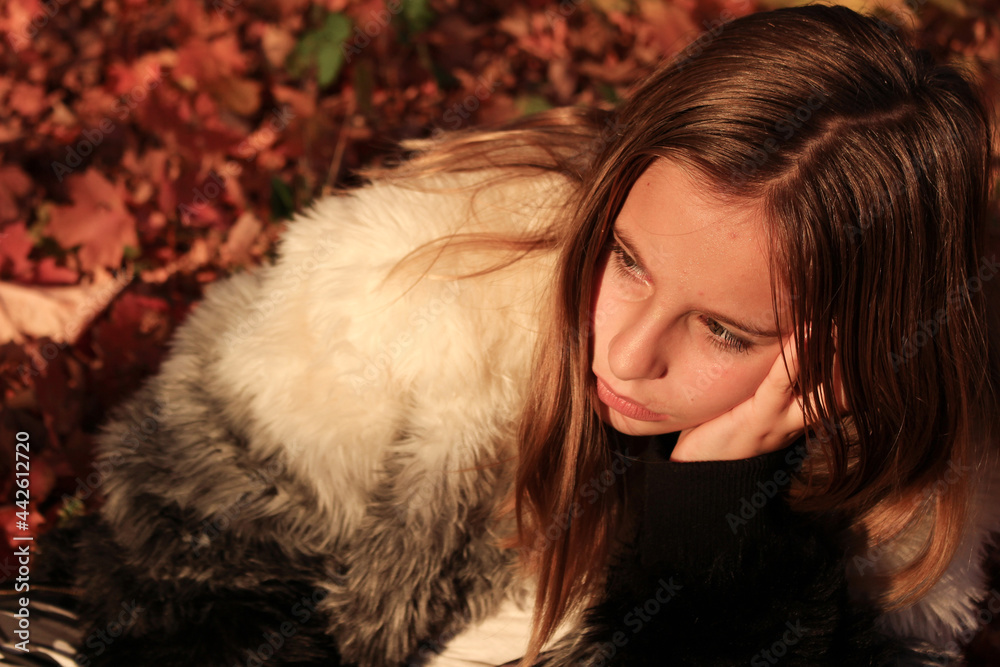 young girl with pensive look sitting in an autumn scene during Fall young girl with pensive look sitting in an autumn scene during Fall