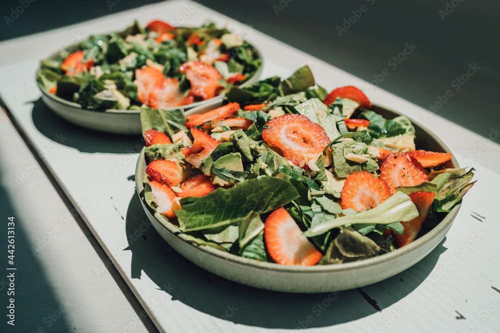 Healthy food at home. Fresh salads lunch meal two plates of kale lettuce and strawberries. Healthy food at home. Fresh salads lunch meal two plates of kale lettuce and strawberries.