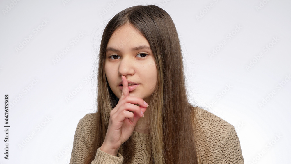 Cute smiling girl holding finger at mouth in shhh gesture after telling secret Cute smiling girl holding finger at mouth in shhh gesture after telling secret