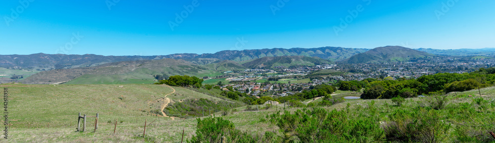Elevated panoramic scenic view of San Luis Obispo urban area sprawl and green mountains of Santa Lucia Range from Bishop Peak Trail on sunny spring day
