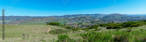 Elevated panoramic scenic view of San Luis Obispo urban area sprawl and green mountains of Santa Lucia Range from Bishop Peak Trail on sunny spring day photo