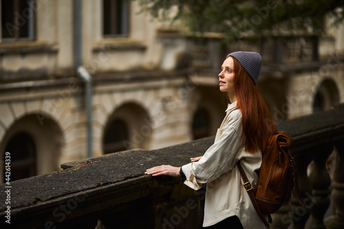 Pretty redhead woman in coat in search of beautiful historical place, looking around, stand in contemplation, exploring new area, young traveler enjoy walking alone, portrait. travel, trip concept