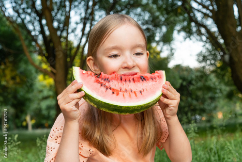 lovely girl on picnic in park, eating ripe red watermelon, taking bite, healthy eating.
