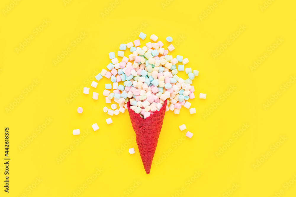 Colorful marshmallow candy in a red waffle ice cream cone on a bright yellow background. Flat lay Colorful marshmallow candy in a red waffle ice cream cone on a bright yellow background. Flat lay