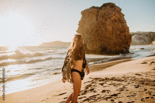 Unrecognizable fit woman in swimsuit standing on sandy beach photo