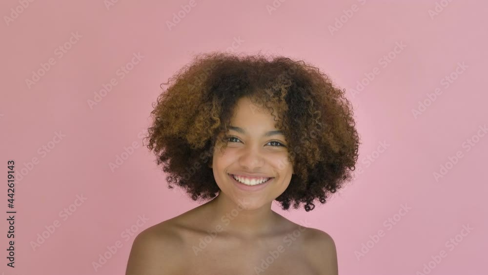 Joyful African American young woman model appears jumping and smiles cheerfully standing against pink background close view Joyful African American young woman model appears jumping and smiles cheerfully standing against pink background close view