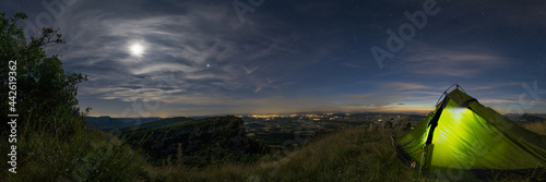 Panoramic view from camp spot with tent on hill over landscape in Provence with fields under the stars at midnight near Eyzahut, France