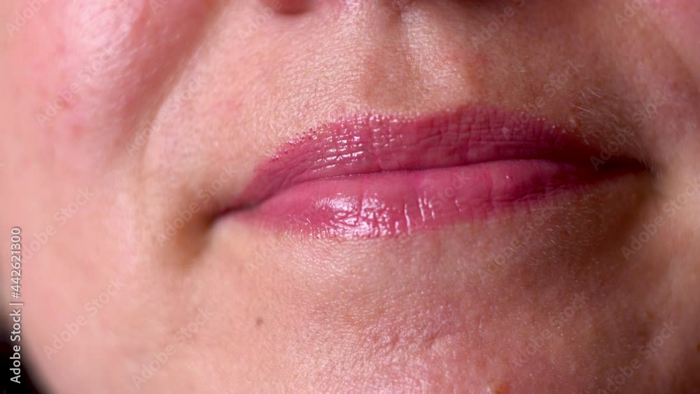 Woman paints her lips with lipstick. Plump lips. Dark skin. Part of the face. Wears makeup. Oriental face type. Close-up. Woman paints her lips with lipstick. Plump lips. Dark skin. Part of the face. Wears makeup. Oriental face type. Close-up.