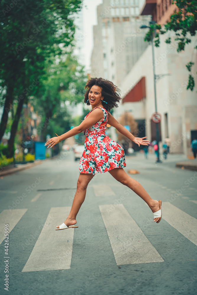 black woman jumping in the city wearing a pink flower dress black woman jumping in the city wearing a pink flower dress