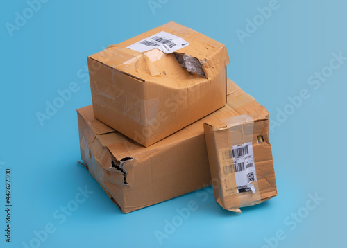 Fotografie Damaged cardboard box with hole on blue background,cardboard box destroyed in sh