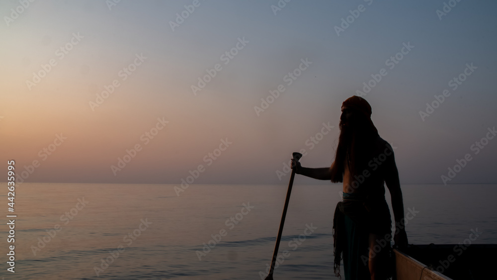 Silhouette of a pirate on the boat sailing into the lake at sunset time in Ontario, Canada.