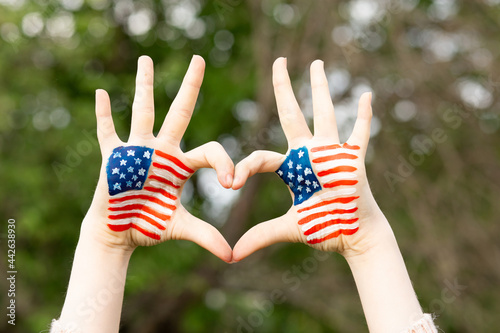 Hands of child painted in American flag color in heart shape. Patriotic holiday. Independence Day, Flag Day, 4th July, 14 June. Little girl show love gesture with hands with USA flag. Constitution Day