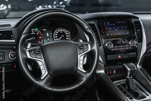 car Interior - steering wheel, shift lever and dashboard, climate control, speedometer, display.