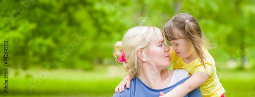Adult woman and little girl with special needs having fun at summer park. Empty space for text