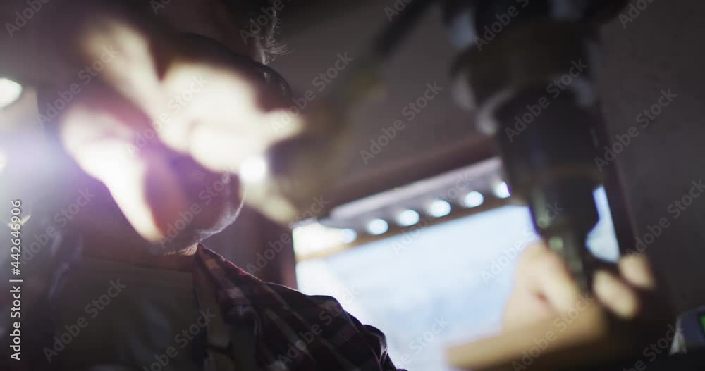 Caucasian male knife maker in workshop wearing glasses using tools to make a knife Caucasian male knife maker in workshop wearing glasses using tools to make a knife