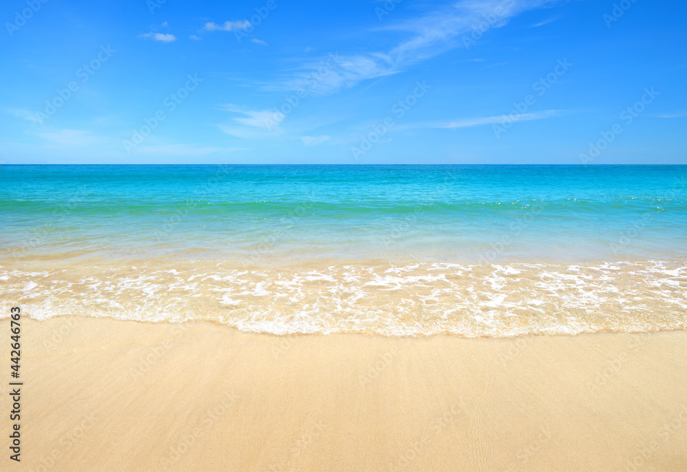 Summer sand beach with ocean waves and blue sky background.
