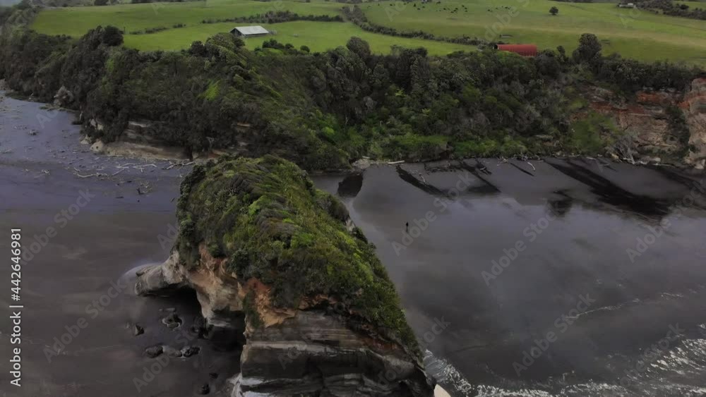 Coastal Cliffs With Caved Rock During Low Tide At Three Sisters And The Elephant Rock In Tongaporutu, New Zealand. - Aerial Pullback Shot Coastal Cliffs With Caved Rock During Low Tide At Three Sisters And The Elephant Rock In Tongaporutu, New Zealand. - Aerial Pullback Shot