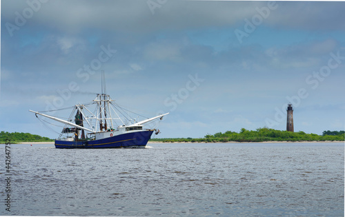 Foto A shrimp boat on the Sabine River heading into the Gulf of Mexico past the histo