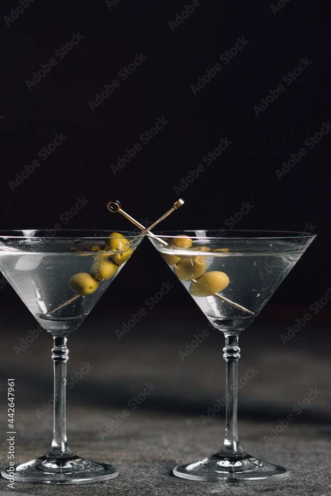 martini glass with olives against black 