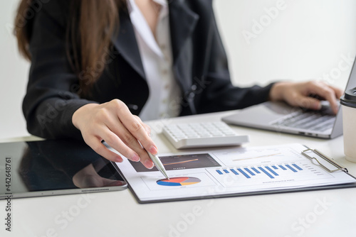 Close-up of a businesswoman hand holding a pen pointing at a chart statistical analysis sitting at the office.