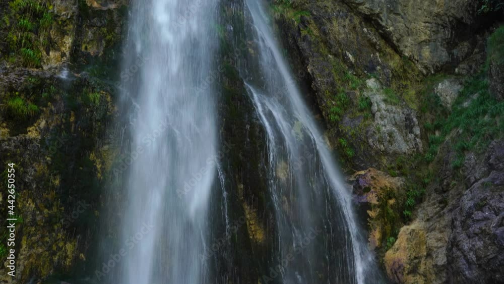 Waterfall inside massive rocky canyon, rain drops falling over cliffs creating rainbow colors Waterfall inside massive rocky canyon, rain drops falling over cliffs creating rainbow colors
