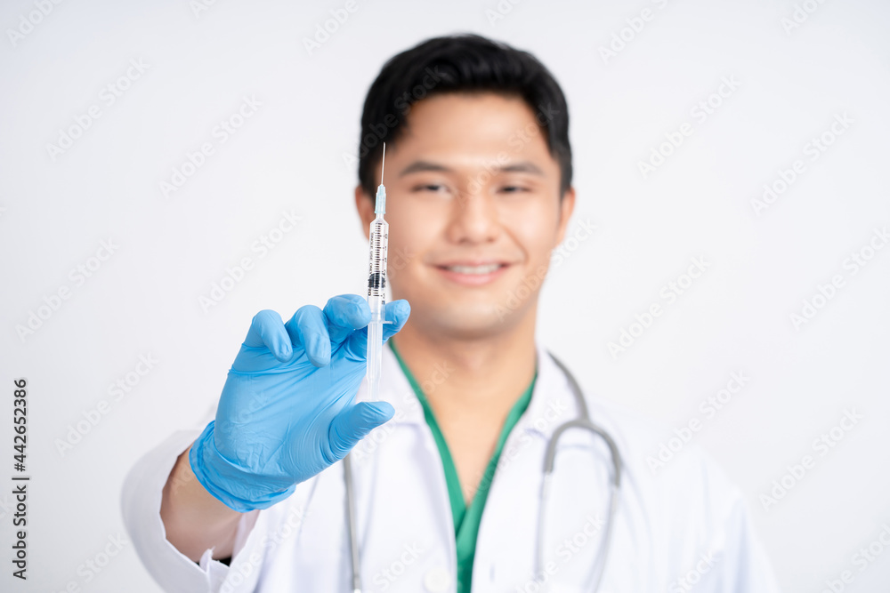 Asian male doctor holding syringe with coronavirus vaccine. He was wearing a protective suit and a mask. Asian male doctor holding syringe with coronavirus vaccine. He was wearing a protective suit and a mask.