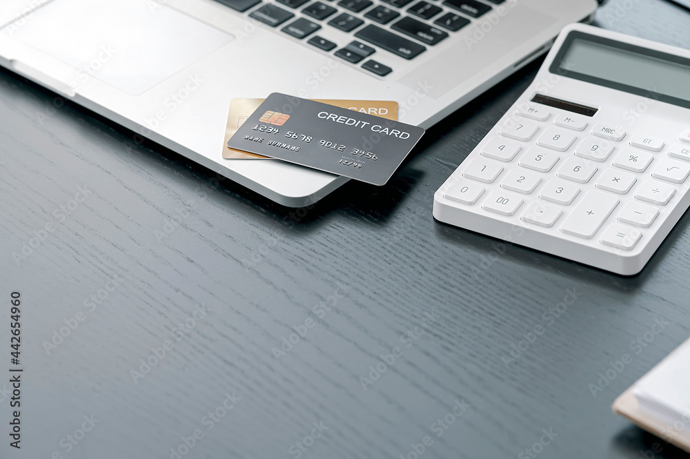 Closeup credit card on laptop computer and calculator on wooden table with copy space. Closeup credit card on laptop computer and calculator on wooden table with copy space.