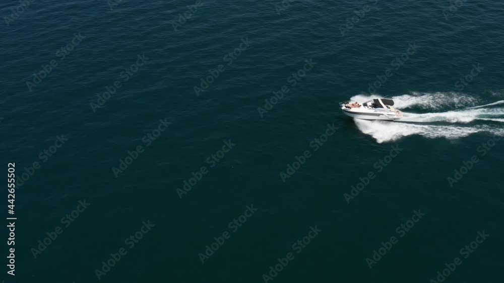 White boat with people movement on blue water aerial view. Large white yacht fast movement on blue water top view. Speed boat with people at high speed. White boat with people movement on blue water aerial view. Large white yacht fast movement on blue water top view. Speed boat with people at high speed.